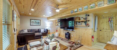 Una habitación con paneles de madera, una mesa de comedor de madera, un sofá, un televisor y una chimenea.