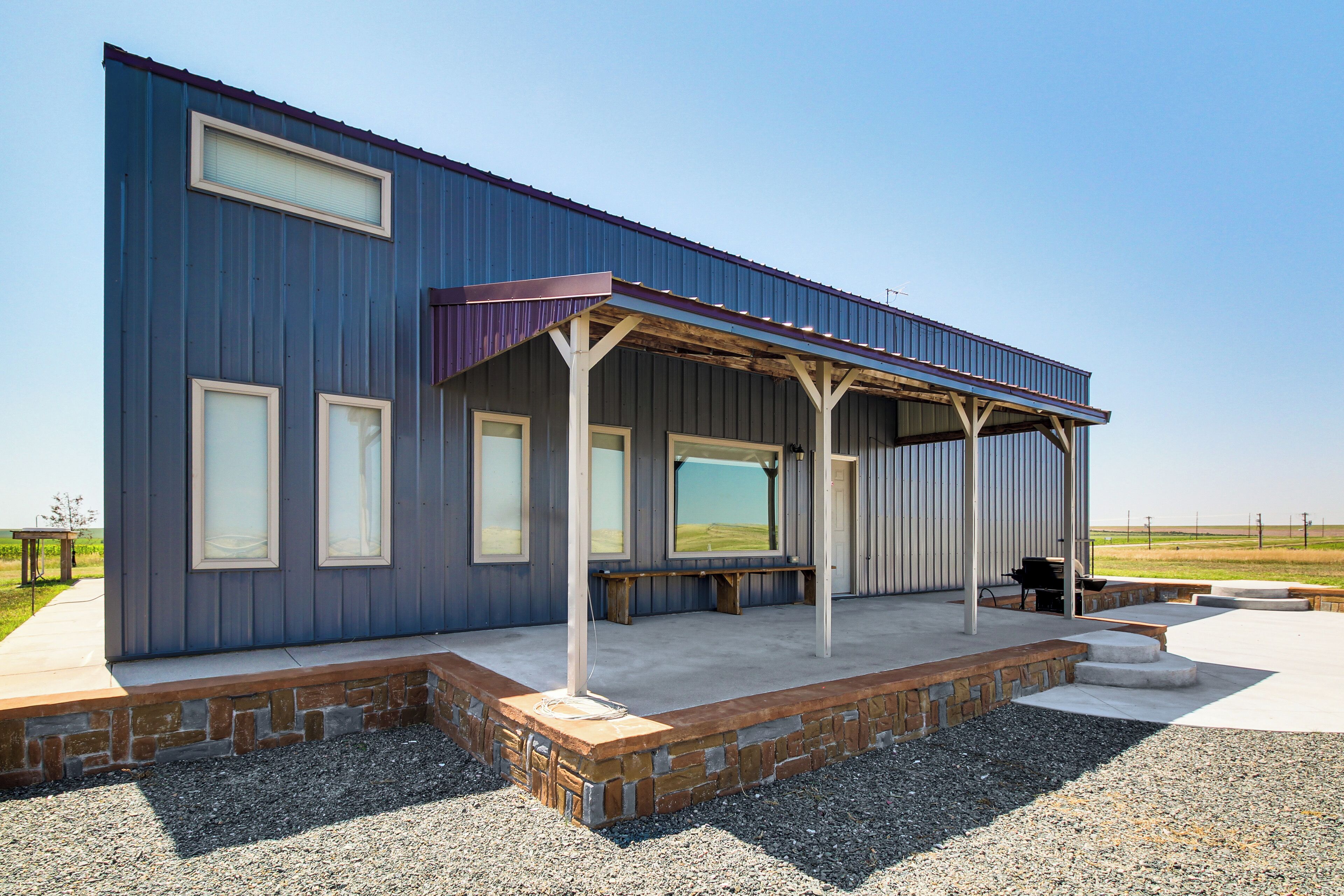 A modern building with a covered patio, large windows, and a stone foundation.