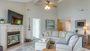 A living room with a fireplace, a sofa, a television, and a ceiling fan. - Lakefront Ozark Getaway w/ Views + Community Perks (Lake Ozark)