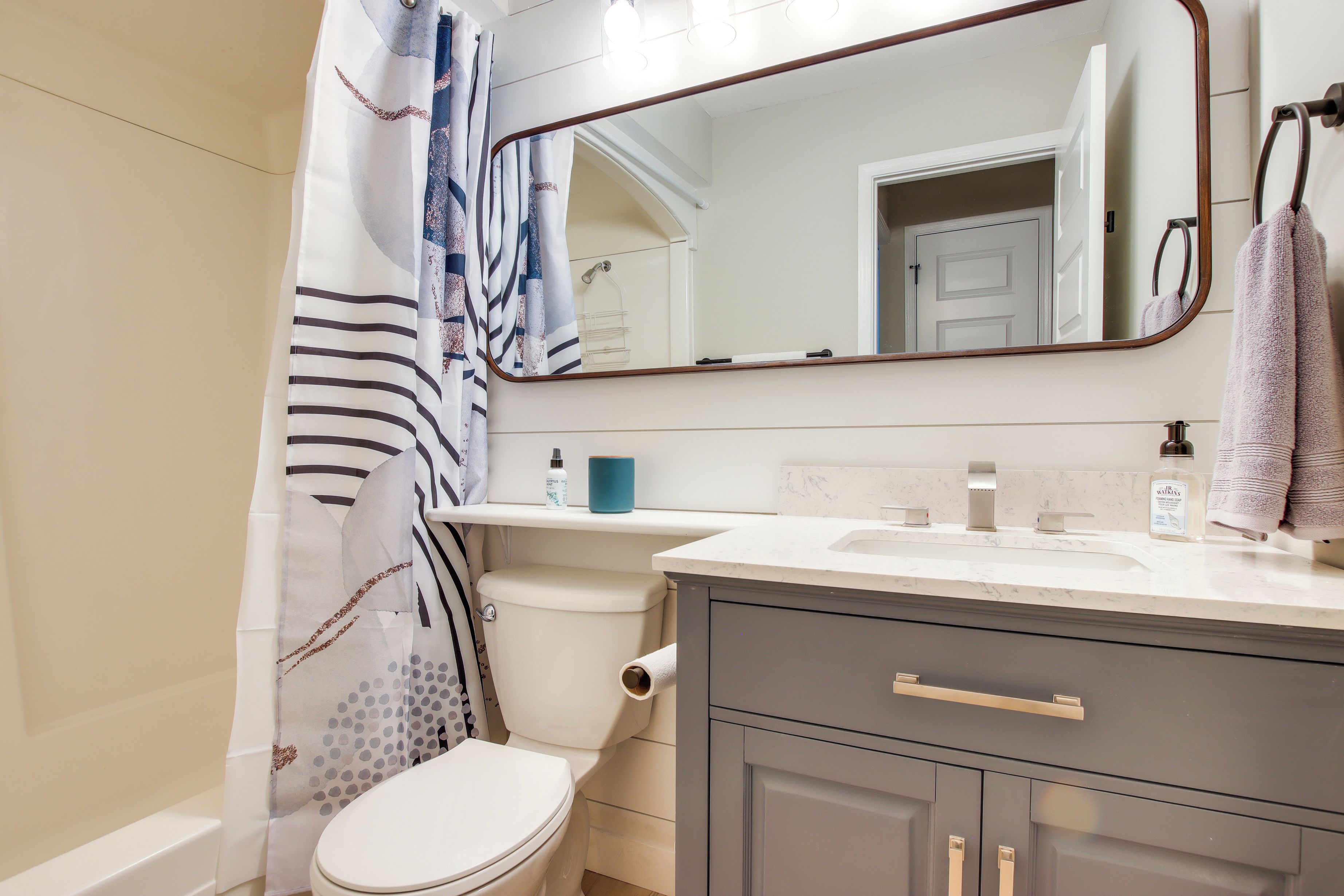 A bathroom with a toilet, sink, mirror, and towel rack.
