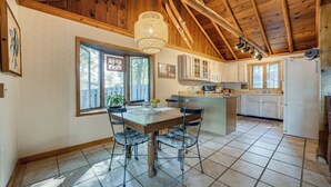 A spacious kitchen with a wooden ceiling, a dining table with chairs, and a large window. - Delton Oasis Retreat w/ Lake Views & Deck! (Delton)