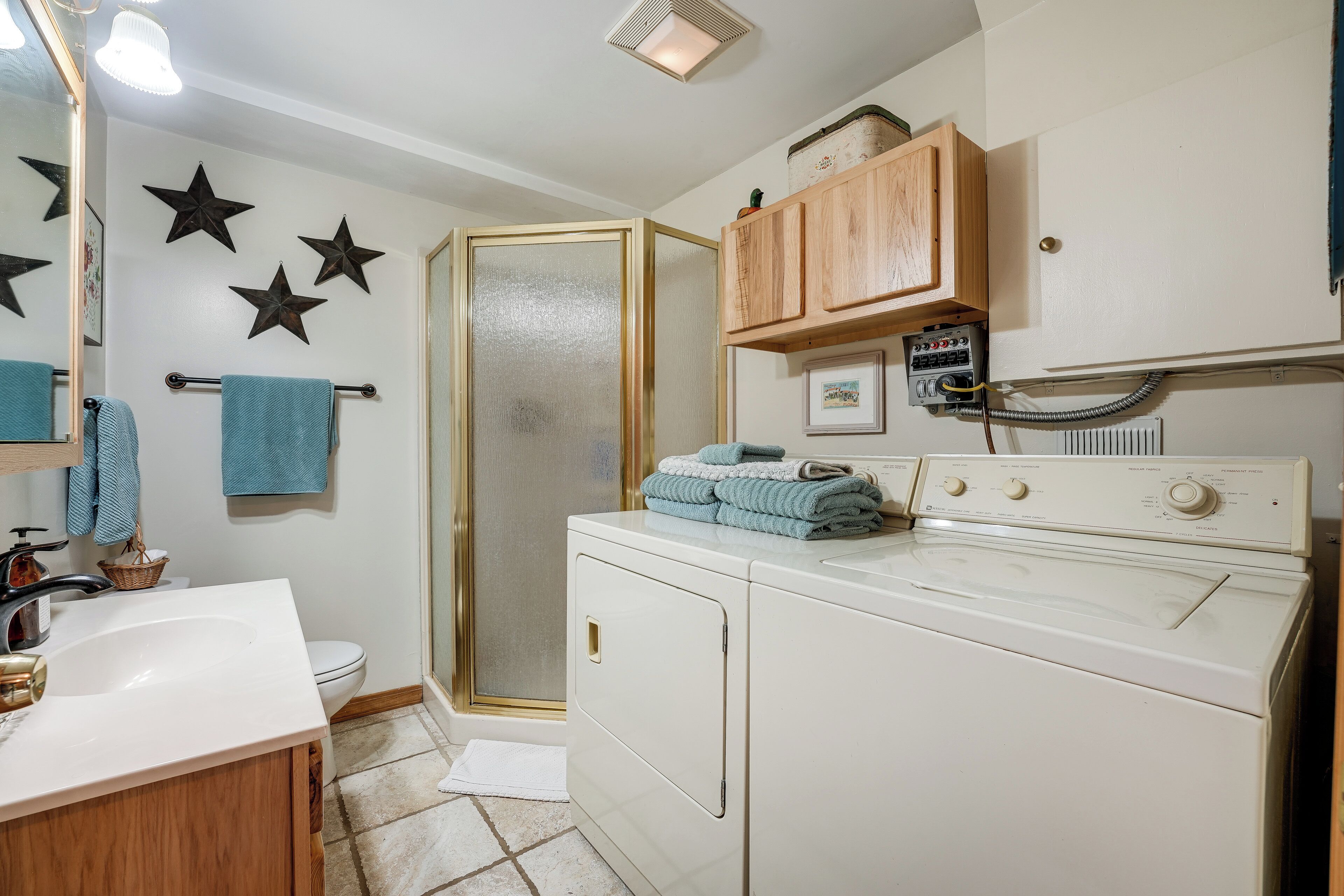 A bathroom with a white sink, a toilet, a shower, and a washing machine.