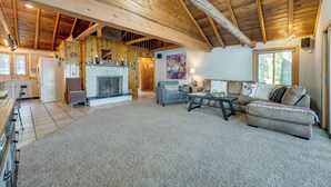 A spacious living area with a fireplace, a sofa, a coffee table, and a dining area with a refrigerator and cabinets. - Delton Oasis Retreat w/ Lake Views & Deck! (Delton)