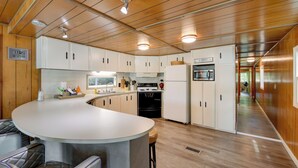 Une cuisine moderne avec des meubles en bois, un îlot central doté de tabourets, un four à micro-ondes et une cuisinière.