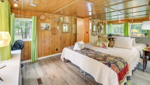 Une chambre à coucher aux murs lambrissés, avec un grand lit, une table de chevet, un miroir et une fenêtre avec des rideaux.
