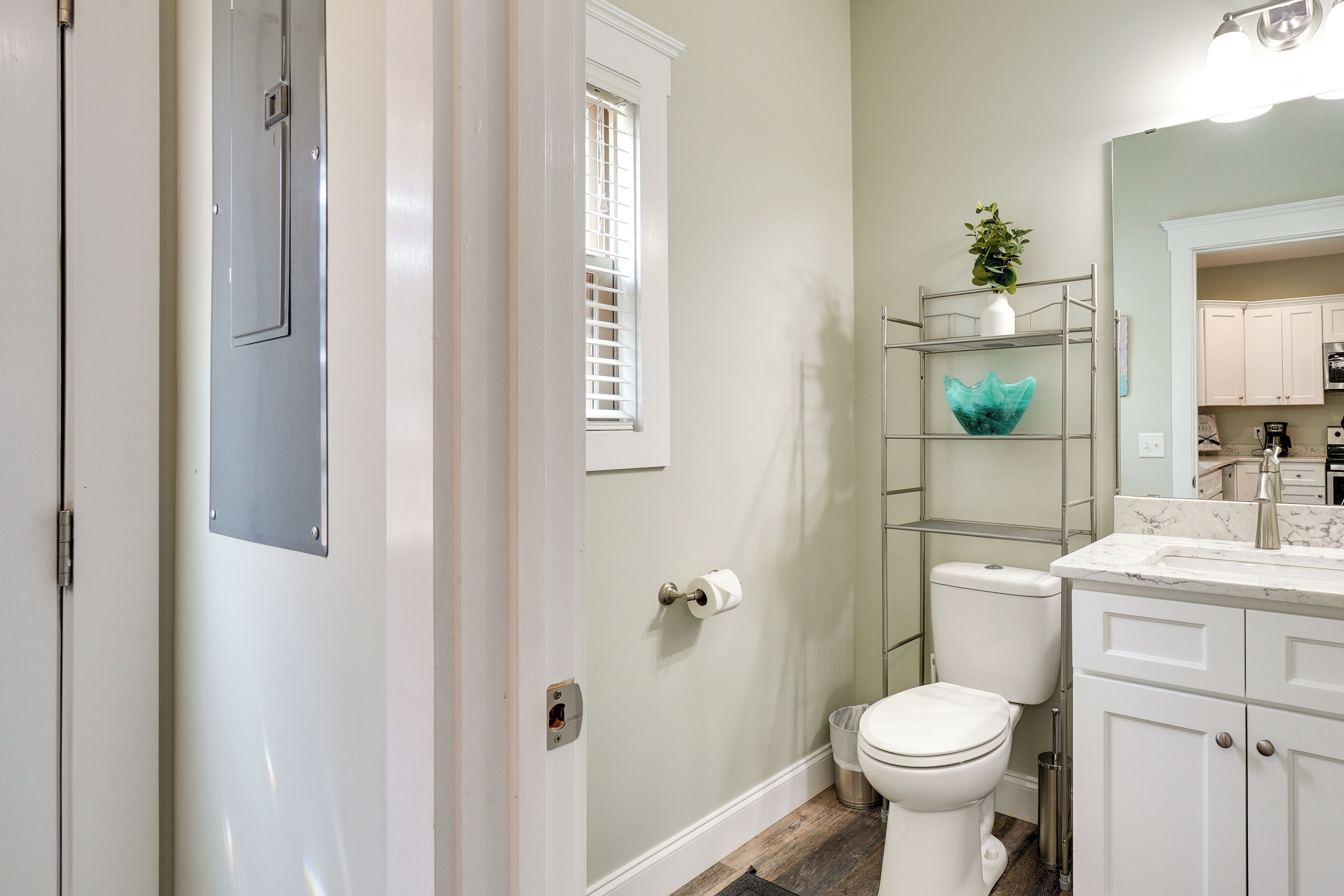A bathroom with a toilet, a shelf with a decorative item, and a sink with a mirror above it.