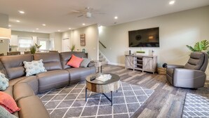 A modern living room with a sectional sofa, a recliner, a coffee table, and a TV mounted on the wall. - Chic Spring City Townhome on Watts Bar Lake! (Spring City)