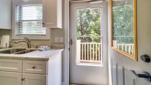 A kitchen with a built-in sink, a marble countertop, and a door leading to a balcony with a view of trees. - Chic Spring City Townhome on Watts Bar Lake! (Spring City)