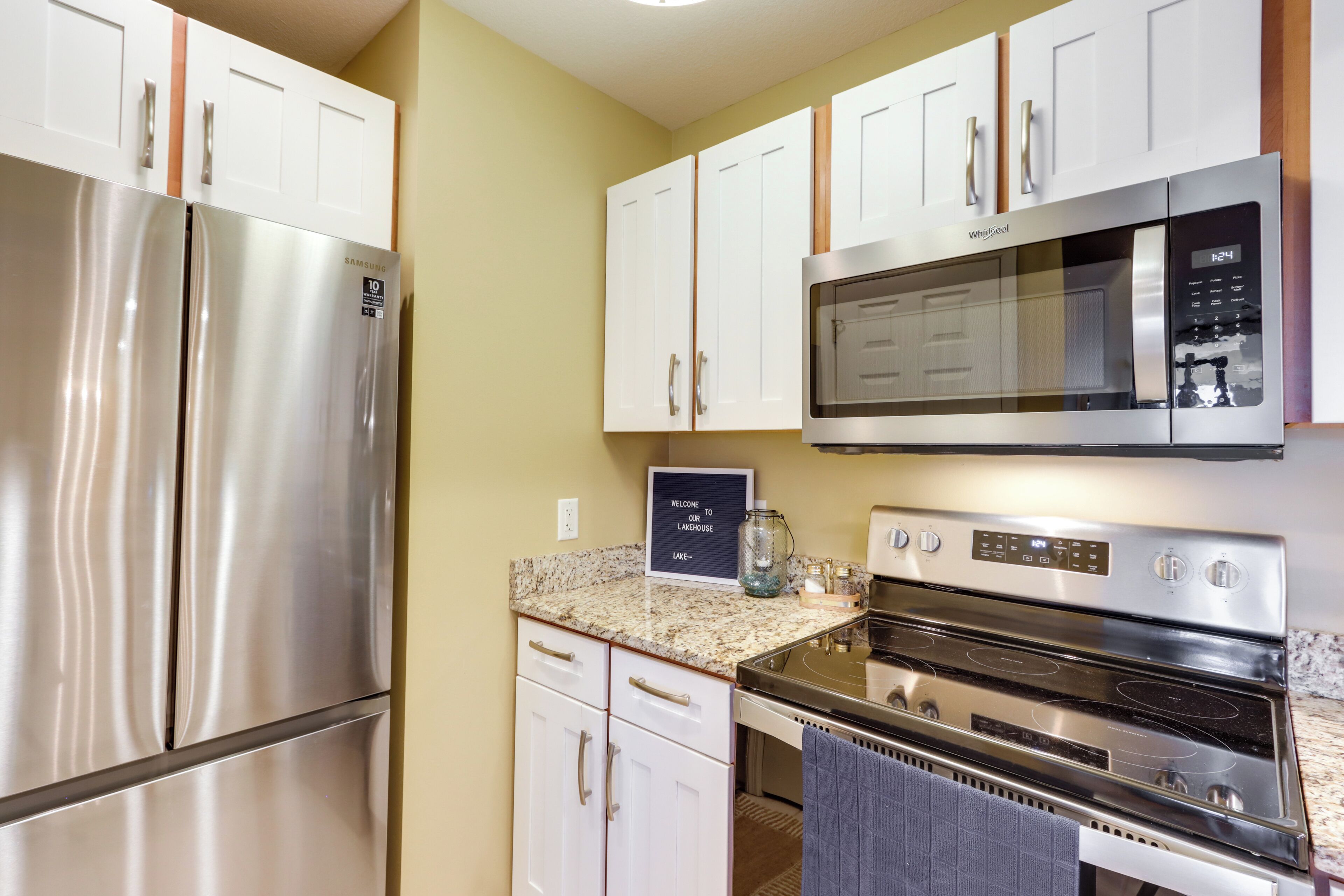 A kitchen with stainless steel appliances, white cabinets, and a granite countertop.