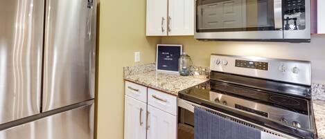 A kitchen with stainless steel appliances, white cabinets, and a granite countertop.