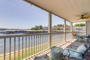 A covered outdoor area with a view of a river, a bridge, and buildings in the background. - Lake Views & Screened Porch: Ozarks Getaway! (Lake Ozark)