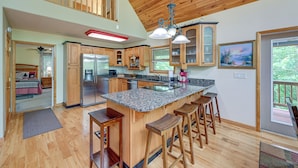 A spacious kitchen with wooden cabinets, a granite countertop, and a central island with bar stools. - Marble Mountainside Escape w/ Wraparound Deck (Marble)