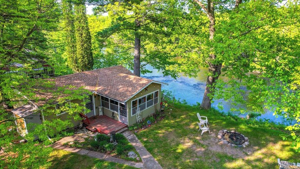 A cabin with a red roof, a porch, and a fire pit. It is surrounded by trees and a lake. - Riverfront Nature Getaway Near Downtown Pine City! (Pine City)