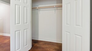 A walk-in closet with a wooden rod and a white door. - Lovely Lake Charles Duplex in Central Location! (Lake Charles)