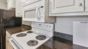 A kitchen with white cabinets, a white stove, and a microwave. - Lovely Lake Charles Duplex in Central Location! (Lake Charles)