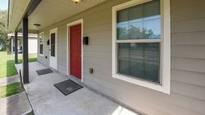 A residential building with a red door, large windows, and a covered porch. - Lovely Lake Charles Duplex in Central Location! (Lake Charles)