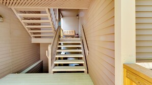 Una escalera de madera que conduce a una zona del segundo piso con un banco y un farol.