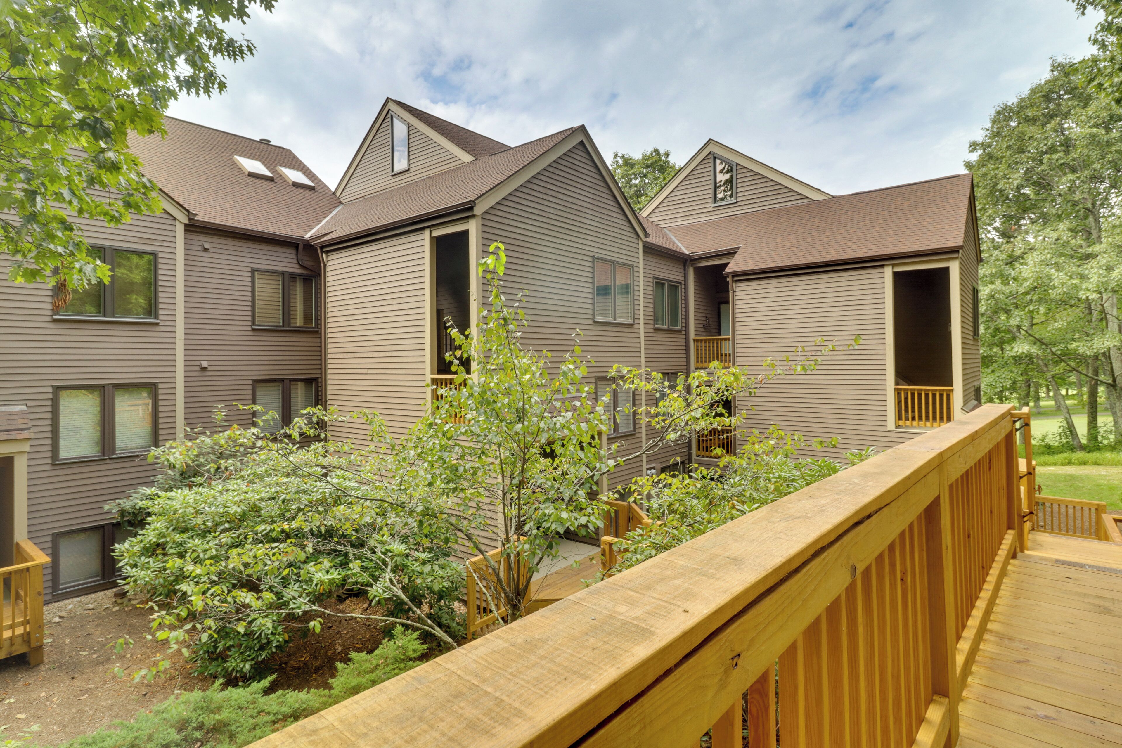 A residential building with multiple entryways and a wooden deck.