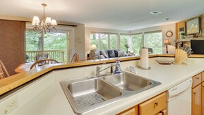 Una cocina moderna con un lavamanos doble, armarios de madera y una zona de comedor con mesa y sillas.