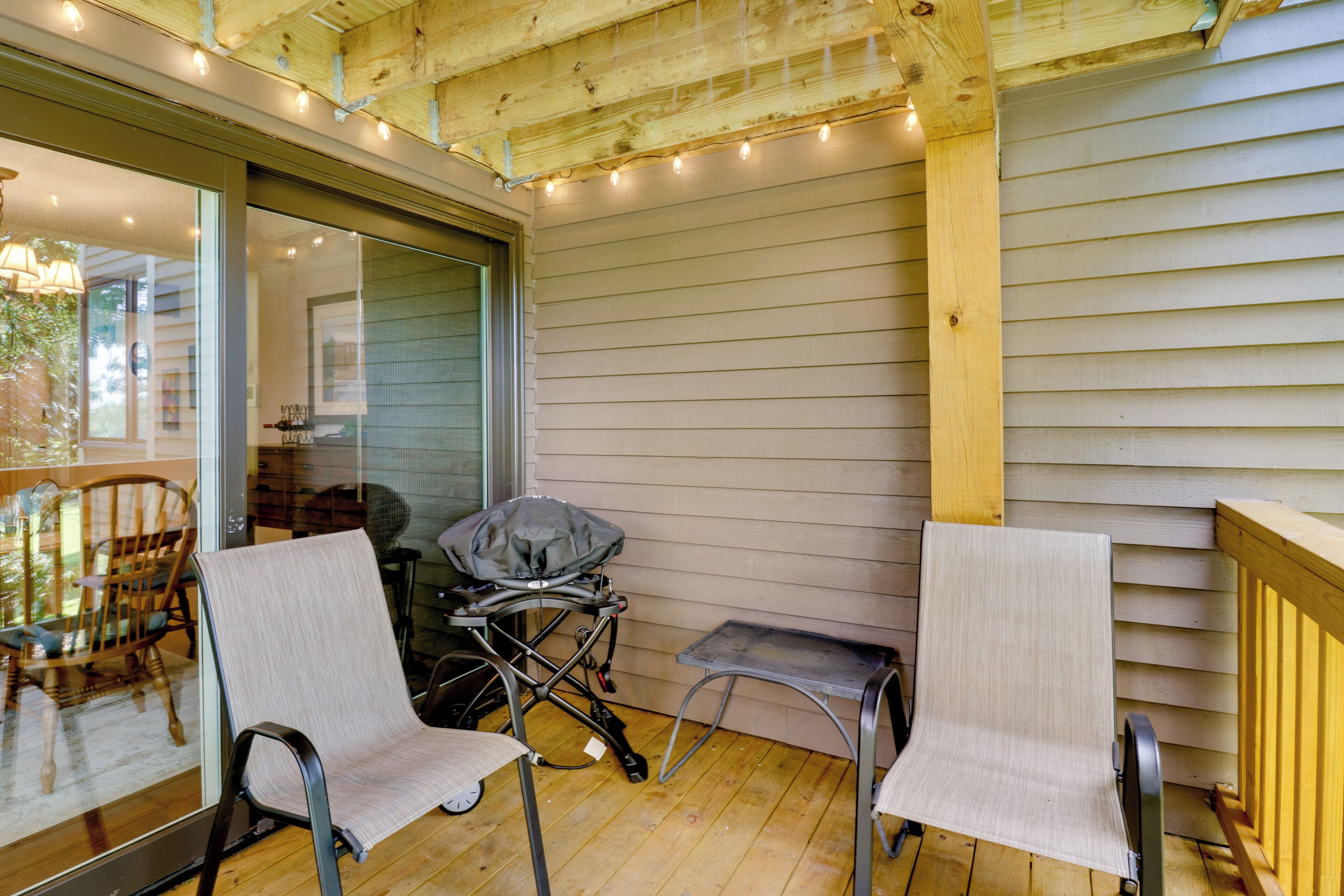 A covered porch with two chairs, a small table, and a stroller.