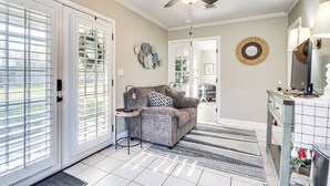 A living room with a sofa, a coffee table, and a ceiling fan. There is a door with glass panels and a rug on the floor. - Walk to Beach: Waveland Retreat w/ Yard! (Waveland)