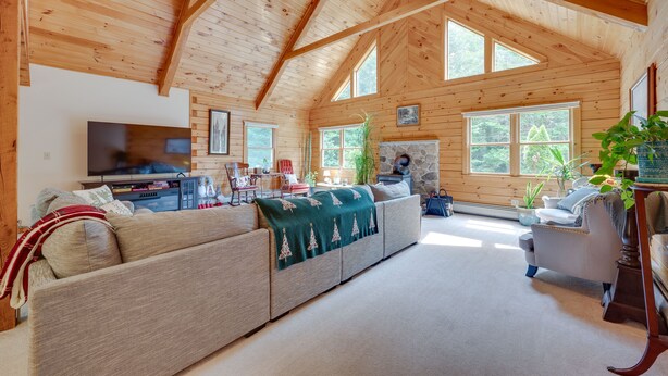 A cozy cabin interior with a large wooden ceiling, a sectional sofa, a television, and a stone fireplace. - Pet-friendly Conway Cabin ~ 5 to Campton Mountain! (Thornton)