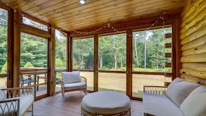 A wooden deck with wicker furniture and a cushioned bench, overlooking a forested area. - Pet-friendly Conway Cabin ~ 5 to Campton Mountain! (Thornton)