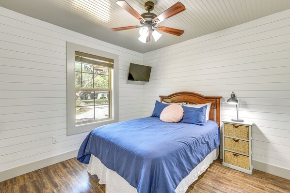 A bedroom with a bed, a ceiling fan, a TV mounted on the wall, and a window. - Pet-friendly Texas Home w/ Furnished Patio & Grill (Graford)