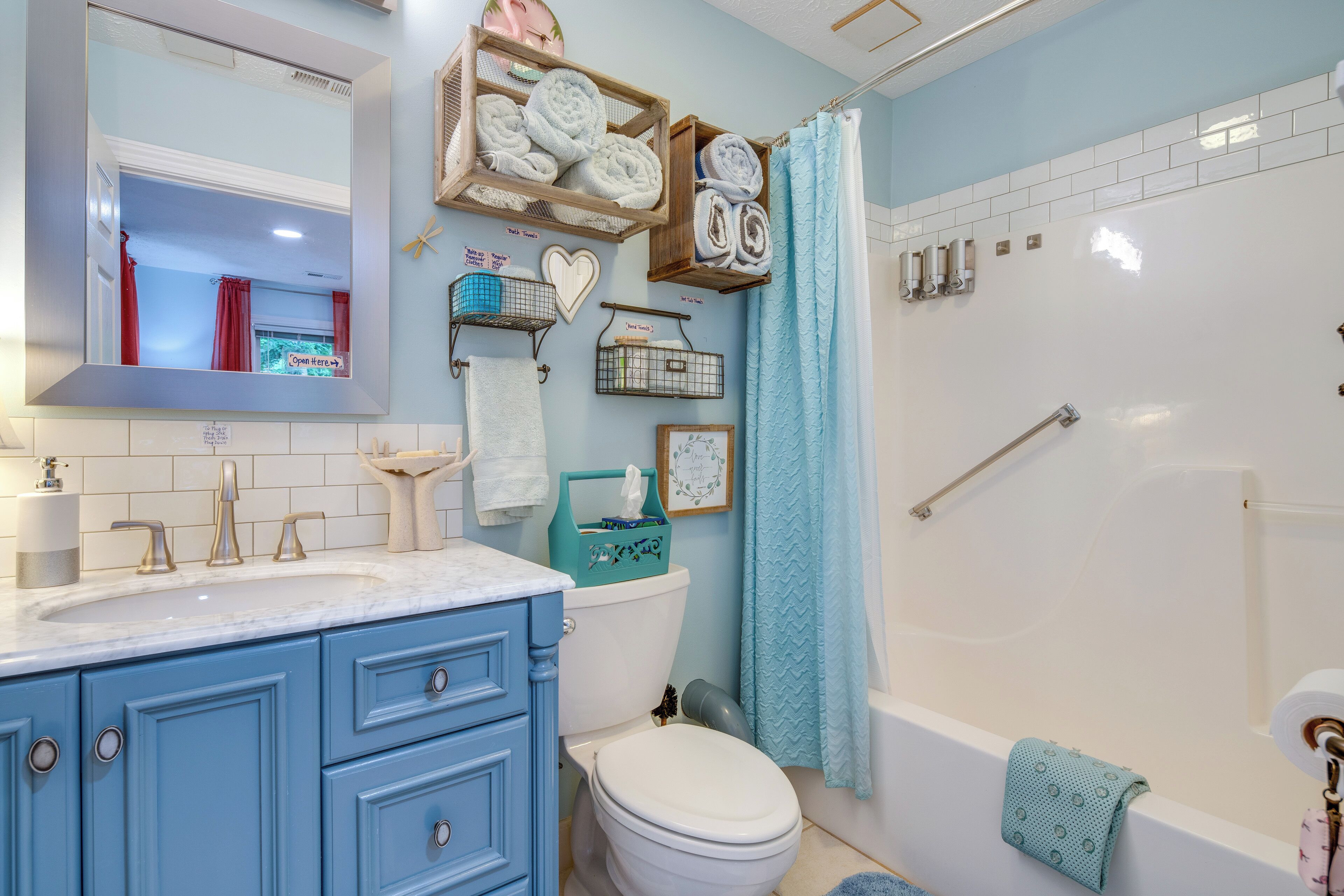 Casa de banho com sanita branca, lavatório azul e chuveiro com cortina azul.