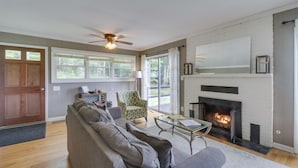 A living room with a fireplace, a sofa, a chair, and a ceiling fan.