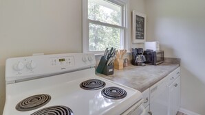 A kitchen with a white stove, a window, and a chalkboard sign.