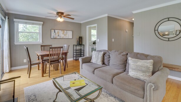 A living room with a sofa, coffee table, and dining area with chairs and a table.