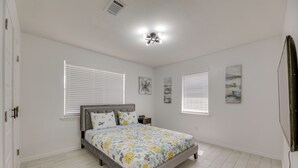 A bedroom with a bed, two bedside tables, and a ceiling light fixture. - Modern Home in Edinburg: Half-mi Walk to Utrgv! (Edinburg)