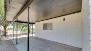 An outdoor covered area with a concrete floor, white brick walls, and a metal roof structure. - Modern Home in Edinburg: Half-mi Walk to Utrgv! (Edinburg)