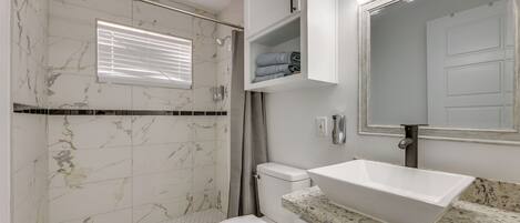A bathroom with a shower, toilet, and sink.