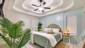 A bedroom with a bed, ceiling fan, bedside table, and a window with blinds. - Welcoming Edinburg Apartment - Pet Friendly! (Edinburg)