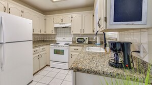 A kitchen with white cabinets, a stove, a microwave, and a coffee maker. - Welcoming Edinburg Apartment - Pet Friendly! (Edinburg)