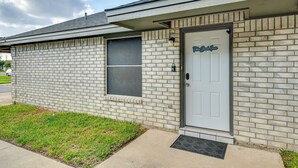 A single-story brick building with a white door and a small window. - Welcoming Edinburg Apartment - Pet Friendly! (Edinburg)