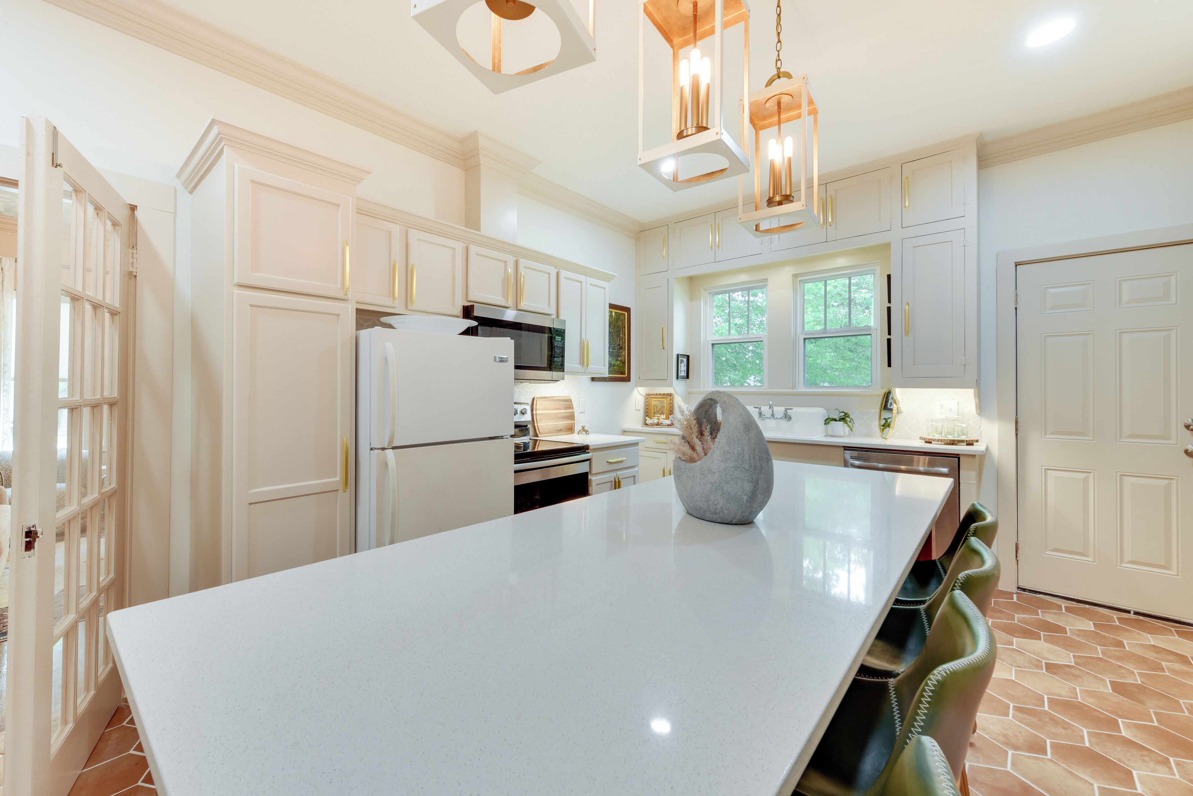 A spacious kitchen with white cabinetry, a large island, and pendant lighting.