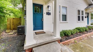 A house with a blue front door, a porch, and a brick border.