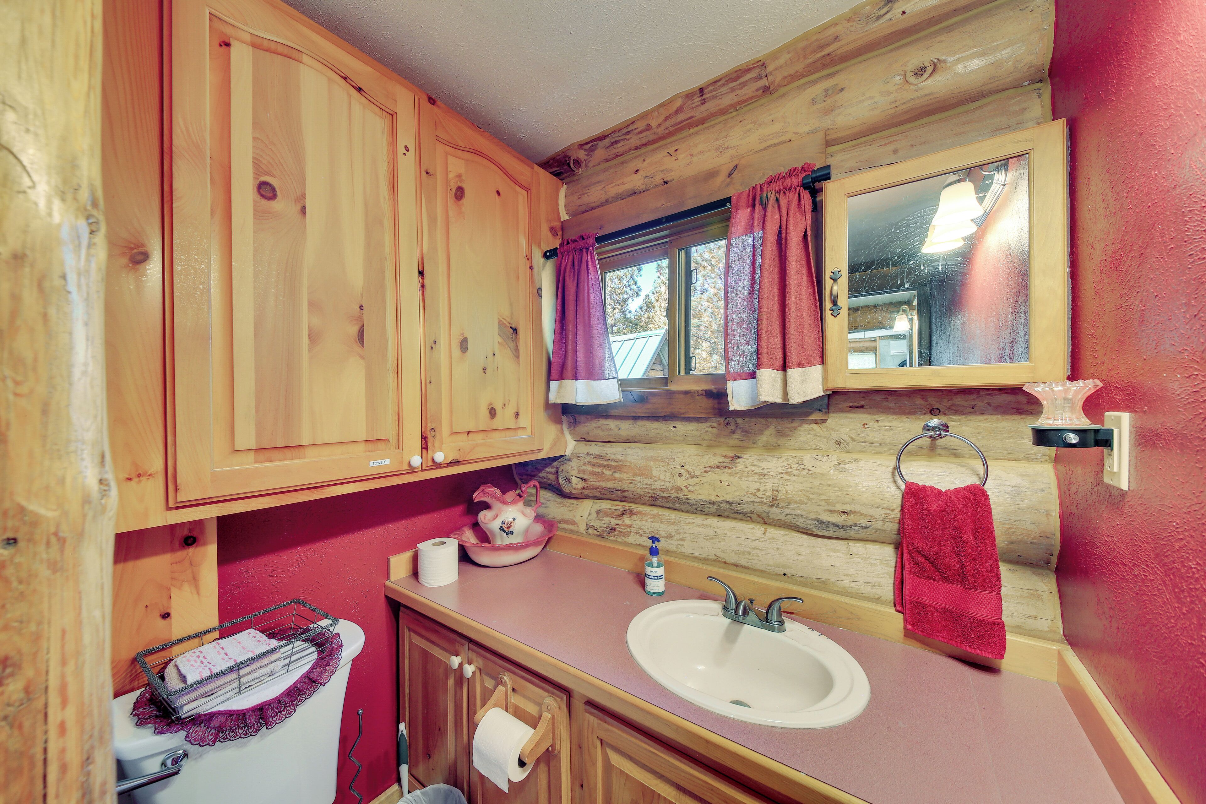 Een houten badkamer in een vakantiehuisje, met een wastafel, toilet en houten kastjes.