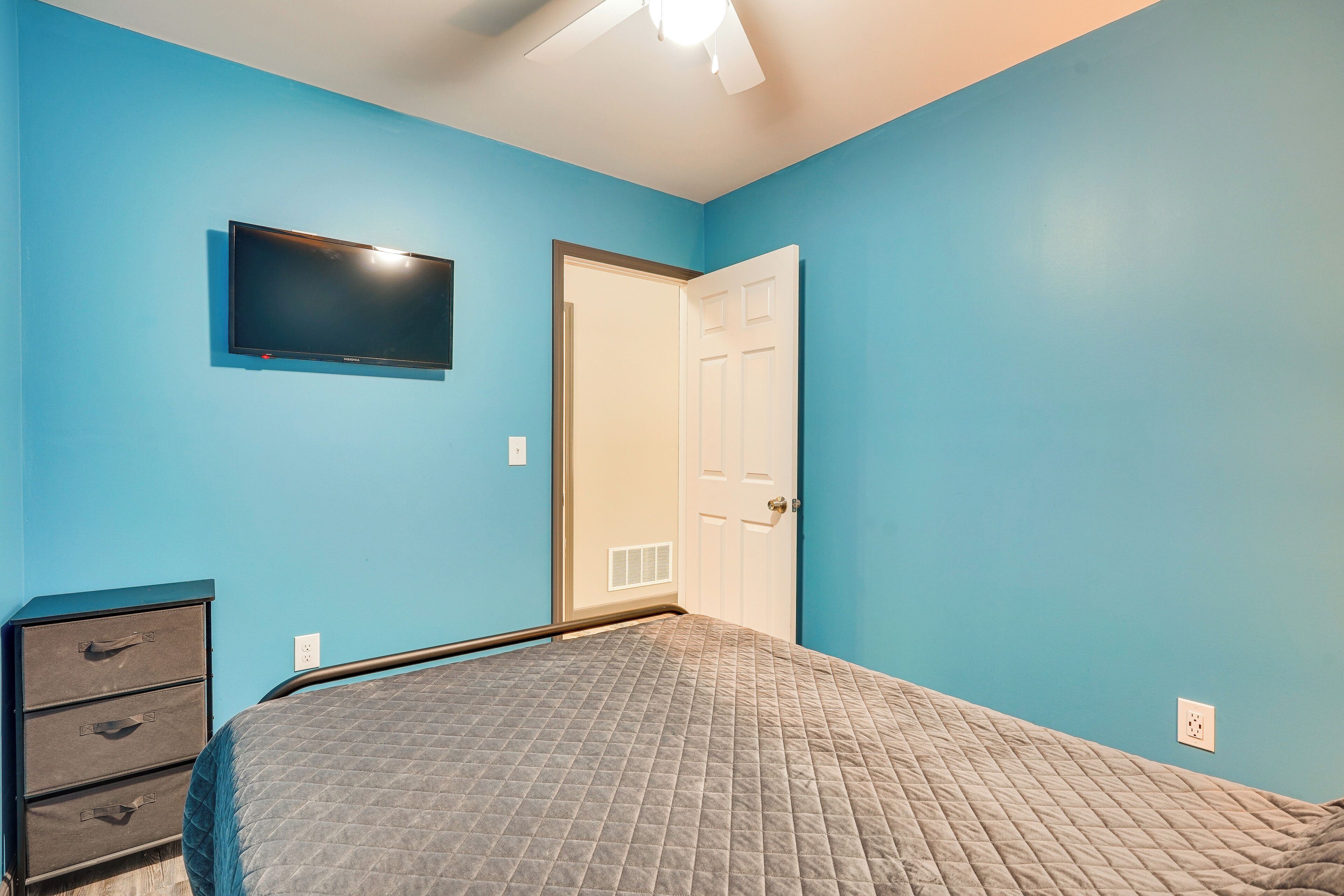 Un dormitorio con cama, cómoda, televisor y puerta.