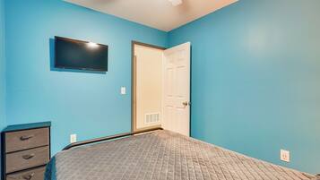 Un dormitorio con cama, cómoda, televisor y puerta.