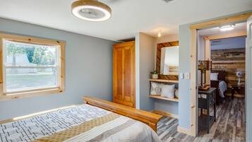 A bedroom with a bed, wooden wardrobe, bedside table, and a window with a view of the outdoors.