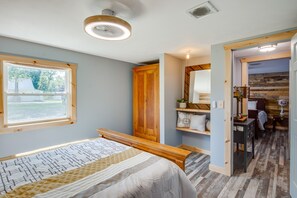 A bedroom with a bed, wooden wardrobe, bedside table, and a window with a view of the outdoors.