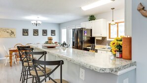 A modern kitchen with a large island, white cabinets, and stainless steel appliances. - Fire Pit & Dock: Lake of the Ozarks Retreat! (Roach)