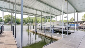 A covered boat dock with multiple moored boats and a clear view of the water. - Fire Pit & Dock: Lake of the Ozarks Retreat! (Roach)