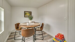 Un comedor con una mesa redonda, cuatro sillas, un jarrón con planta y un cuadro en la pared.