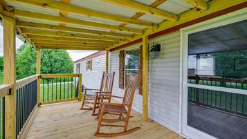 Relax on the covered porch with three comfortable rocking chairs, surrounded by a well-manicured lawn.