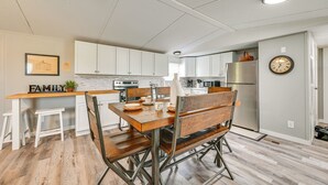 Una cocina moderna con armarios blancos, una mesa de comedor de madera y un banco empotrado.